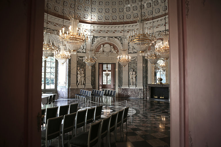 View into the domed hall with several rows of chairs and illuminated chandeliers