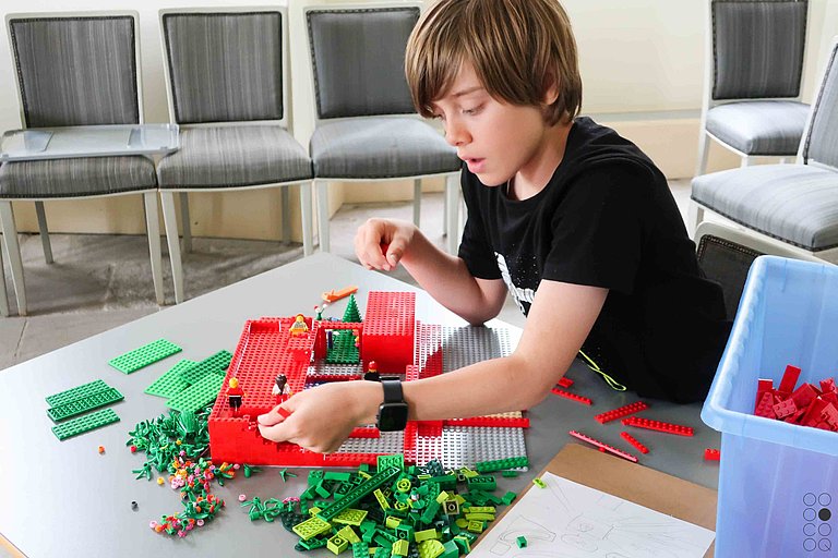 Ein Junge baut mit Legosteinen ein Gebäude