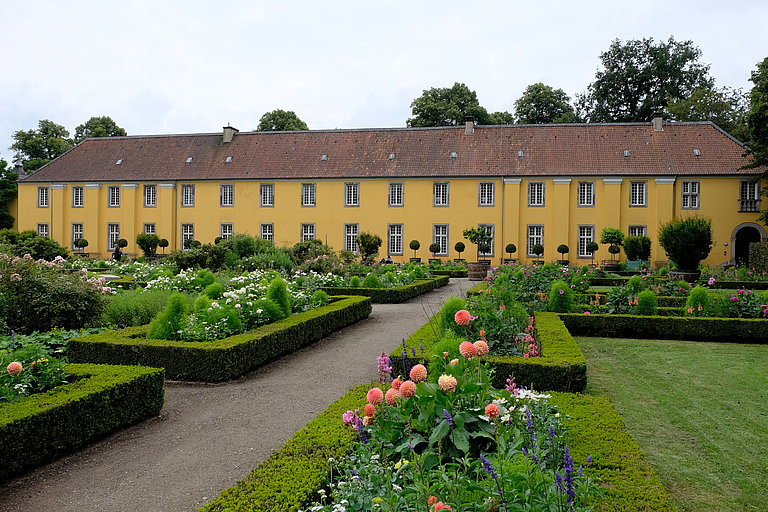 Parterre garden with different coloured flowers and view of the orangery