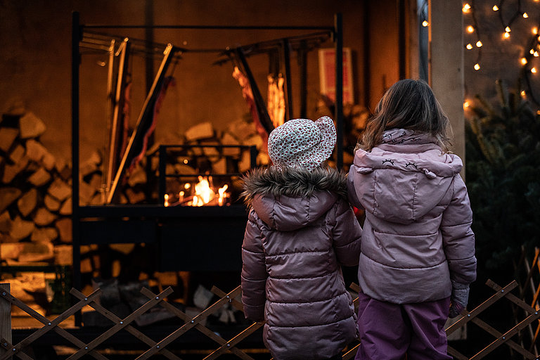 Two children in front of a lit fireplace